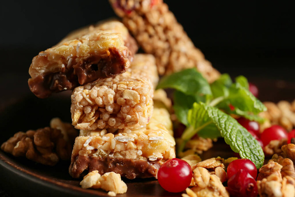 Plate with healthy cereal bars and cranberries on dark background - Photo, Image