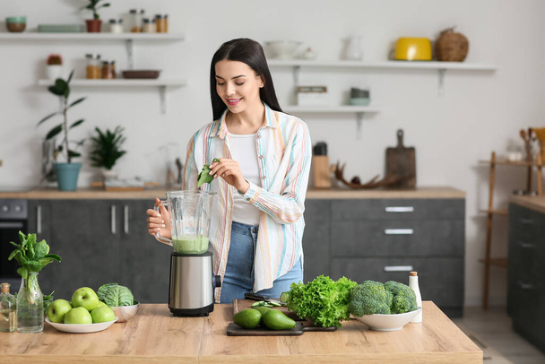 Mujer joven preparando batido verde saludable en la cocina - Foto, imagen