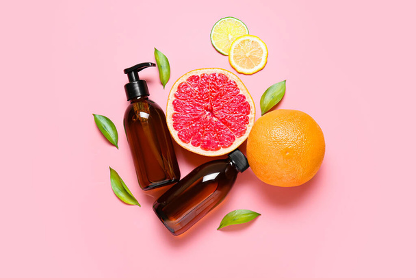 Samenstelling met flessen etherische olie en citrusvruchten op kleur achtergrond - Foto, afbeelding