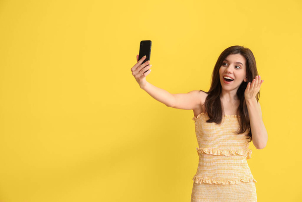 Renkli arka planda selfie çeken zarif genç bir kadın. - Fotoğraf, Görsel