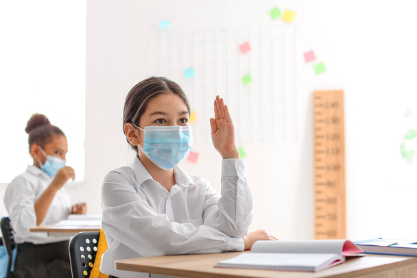 Cute little girl wearing medical mask during lesson at school - Photo, Image