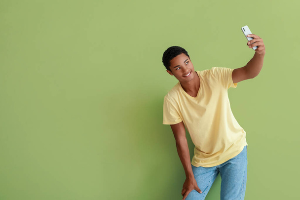 Glücklicher afroamerikanischer Teenager macht Selfie auf farbigem Hintergrund - Foto, Bild