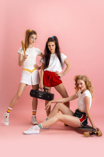 Pretty young women in retro 90s fashion style, outfits posing isolated over pink studio background. Concept of eras comparison, beauty, fashion and youth. - Photo, Image