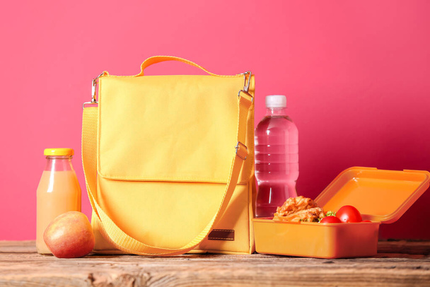 カラーを背景にした木のテーブルの上のランチボックスバッグや食べ物 - 写真・画像