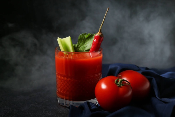 Glass of bloody mary cocktail garnished with red chili pepper and tomatoes on dark background - Photo, Image