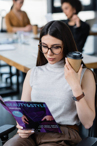 brunette businesswoman with coffee to go reading beauty and style magazine - Photo, Image