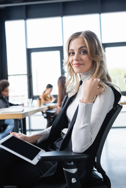 mladá a šťastná podnikatelka sedící na kancelářské židli s digitálním tabletem - Fotografie, Obrázek