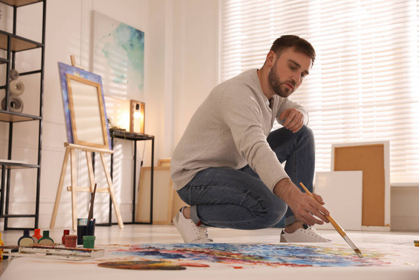 Young man painting on canvas with brush in artist studio - Photo, Image