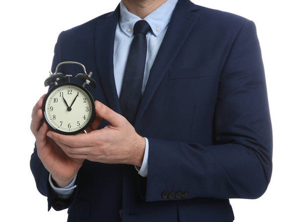 Businessman holding alarm clock on white background, closeup. Time management - Valokuva, kuva
