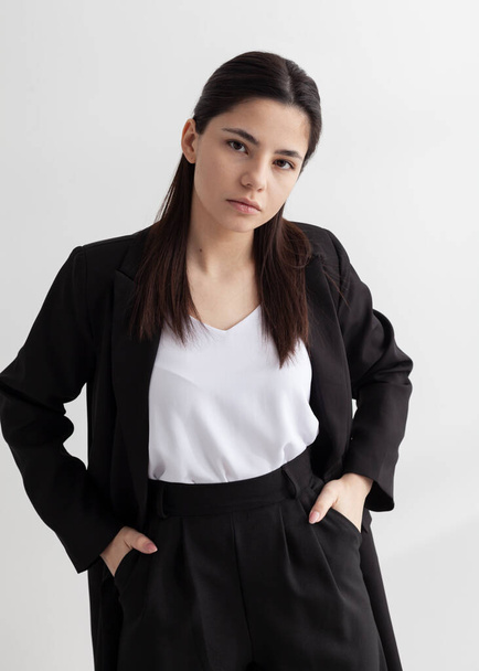 beautiful brunette in an office suit on a light background - Zdjęcie, obraz