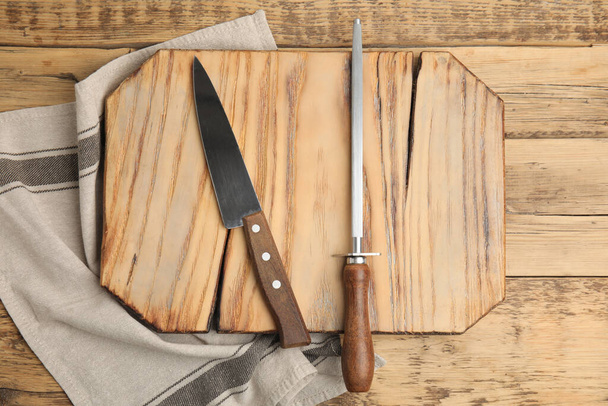 Sharpening steel and knife on wooden table, top view - Foto, Imagem