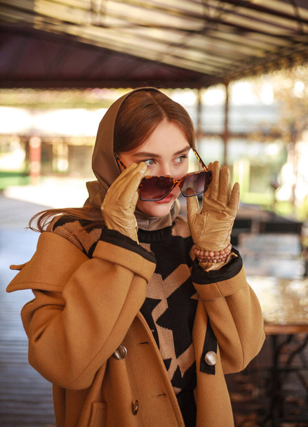 Fashionable young lady in a long beige coat at the restaurant site, autumn clothing style - Foto, immagini
