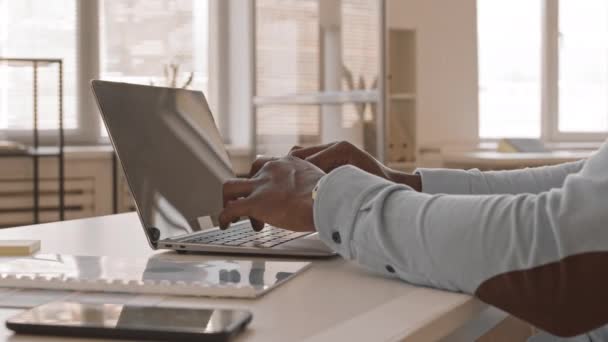 Detailní záběr rukou na nerozpoznatelného pracovníka mužské kanceláře, který sedí za stolem a píše na klávesnici přenosného počítače - Záběry, video