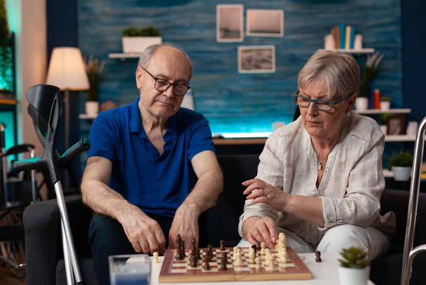 Senior mężczyzna i kobieta koncentruje się na pokładzie mecz gry - Zdjęcie, obraz