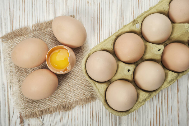Vista de cerca de los huevos de pollo crudos en la caja de huevos sobre fondo de madera. Huevos de pollo crudos en caja de huevo alimentos orgánicos para una buena salud alta en proteínas . - Foto, Imagen