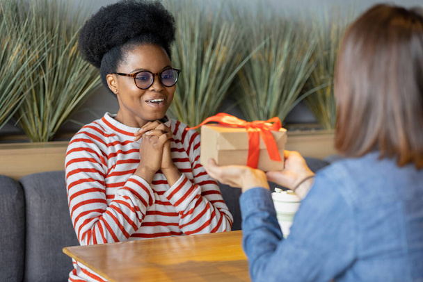 millennial African American woman receives gift from her girlfriend - 写真・画像