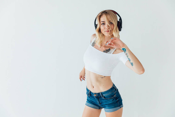 mujer rubia bailando música en auriculares en el entrenamiento - Foto, Imagen