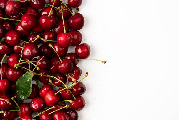 Cherry Red čerstvé třešně v bílém pozadí a pár třešní na stole, roztroušené třešně - Fotografie, Obrázek