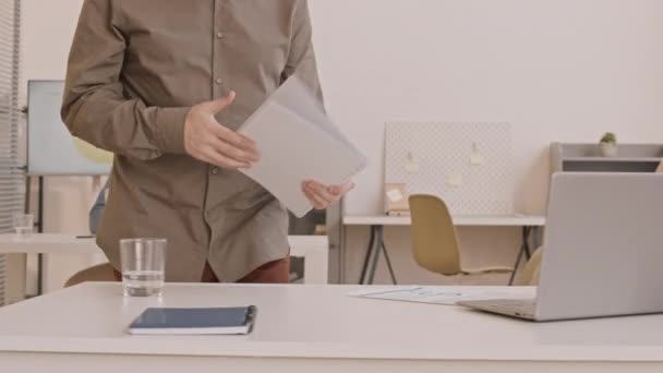 Відстежуючи право каукасівського клерка, який несе документи до свого столу, сідає на стілець і починає працювати на переносному комп "ютері - Кадри, відео