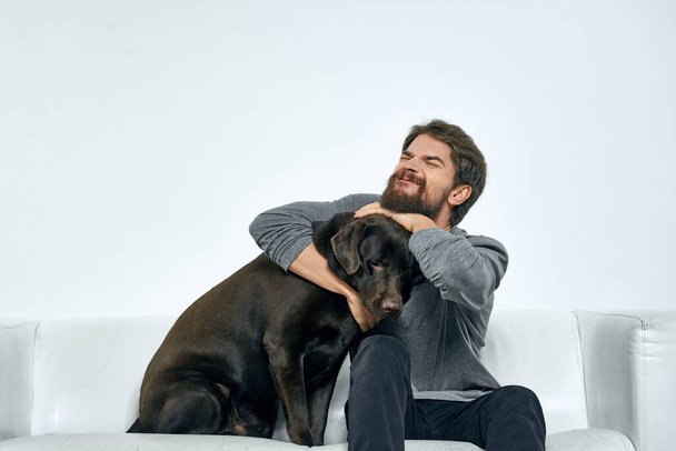 Cheerful man playing at home on the couch with dog fun emotions - Foto, imagen