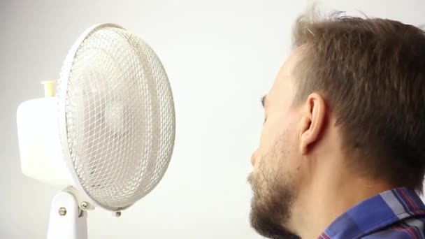 muž uniká z letního vedra před ventilátorem, lidská tvář blízko pracovního starého ventilátoru, těší chlad, bílé pozadí - Záběry, video