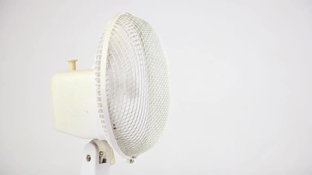 ventilador de ventilador branco rotativo no lado esquerdo no fundo branco, ar condicionado elétrico e resfriamento de verão, vista frontal de close-up - Filmagem, Vídeo