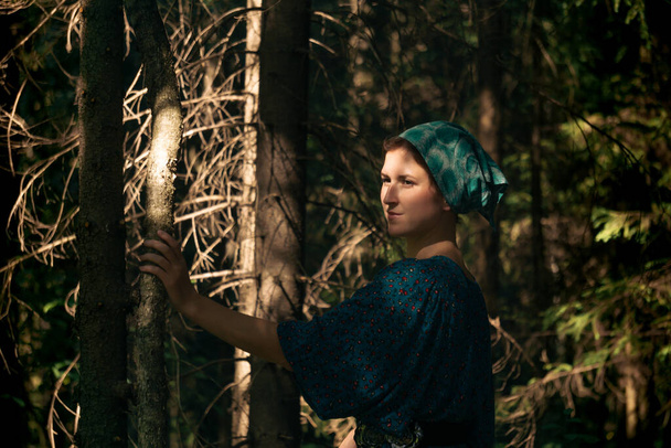 jonge vrouw in traditionele folk boer jurk en hoofddoek in naaldbos - Foto, afbeelding