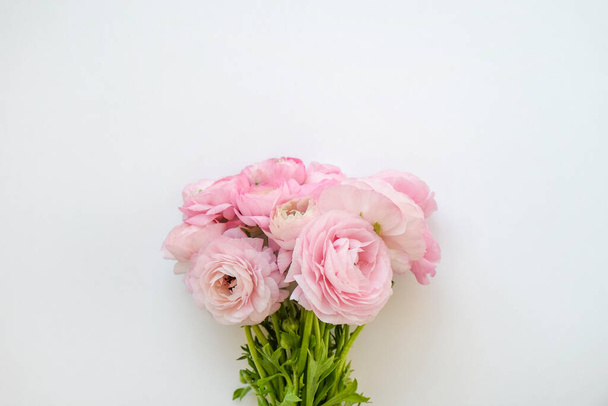 Studio shot of beautiful bouquet of pale pink ranunculus flowers with visible petal texture. Close up composition with bright patterns of flower buds. Top view, isolated, copy space. - Photo, Image