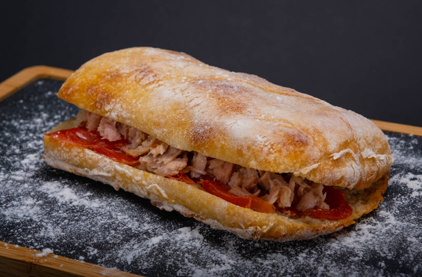 Ciabatta szendvics tonhallal, krémsajttal és paradicsommal fából készült tálcán - Fotó, kép
