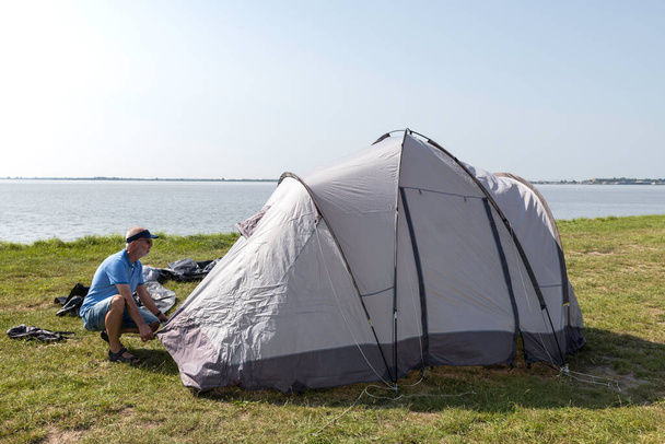 man setting up a tent at the waterline - Zdjęcie, obraz