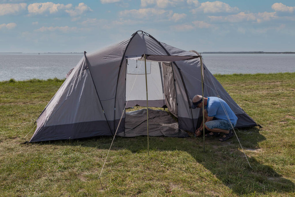 man setting up a tent at the waterline - Photo, image