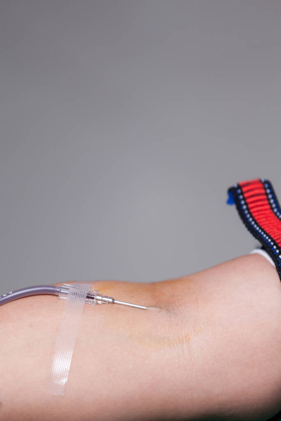 Arm of blood donator with needle and rubber tube in blood donation activity. - Foto, imagen