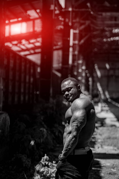 Handsome strong bodybuilder outdoor looking to his side. Black and white picture of muscular man. - Фото, изображение