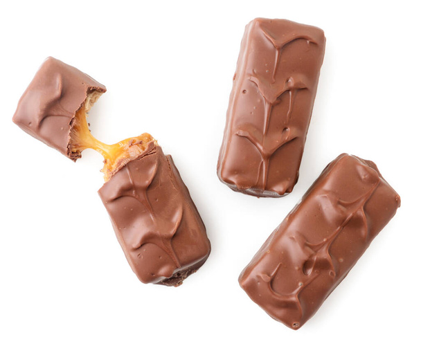 Chocolate bar with nougat and caramel, whole and broken close-up on a white background, isolated. Top view - 写真・画像