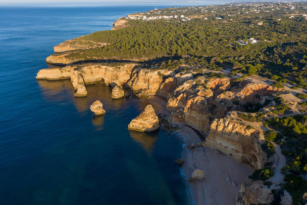 Słoneczny dzień na plaży w Algarve w Portugalii z turkusowym morzem w tle. Z lotu ptaka widać klify Algarve. Widok z lotu ptaka. Pojęcie podróży w Portugalii i najpiękniejszych miejsc w Portugalii. - Zdjęcie, obraz