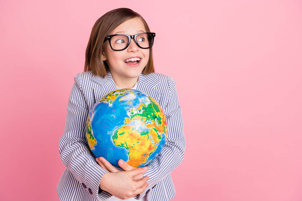 Portrait of attractive cheerful girl hugging globe looking aside copy space isolated over pink pastel color background - Foto, afbeelding