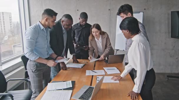Verscheidene multiraciale business team en Kaukasische vrouw mentor leider brainstorm papierwerk talk bespreken teamwork corporate briefing in kantoor, jonge vrouwelijke baas uit te leggen nieuwe project plan training vergadering - Video