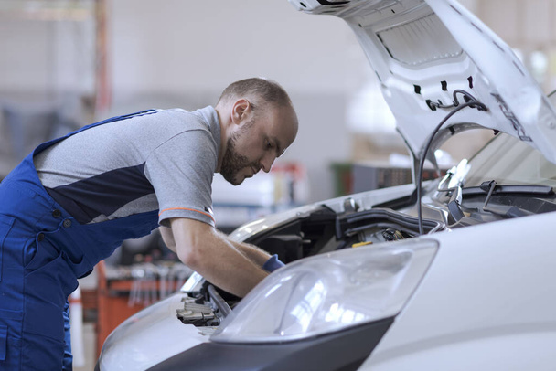 Professional mechanic checking a car engine, car repair service concept - Valokuva, kuva