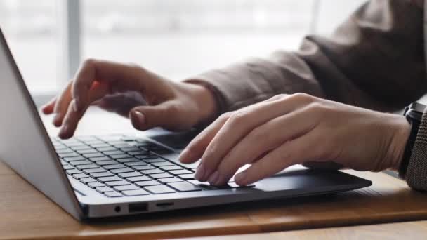 Крупный план женских рук кавказской студентки, печатающей на клавиатуре ноутбука за столом в домашнем офисе. Неузнаваемая женщина носит куртку и электронные часы на запястье, работая в компьютерном чате онлайн - Кадры, видео