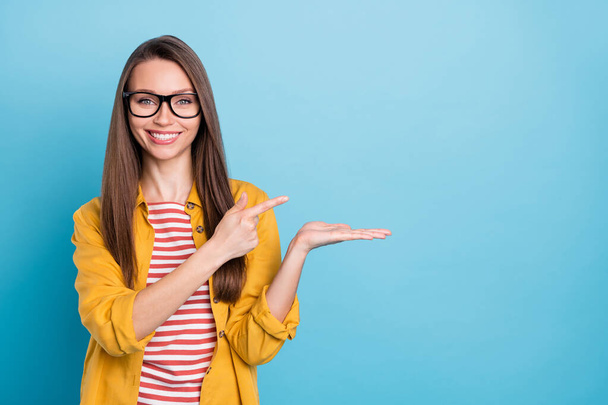 Фотографія молодої жінки щаслива позитивна точка посмішки палець продукт реклами вибір продажу ізольовані на синьому кольоровому фоні
 - Фото, зображення