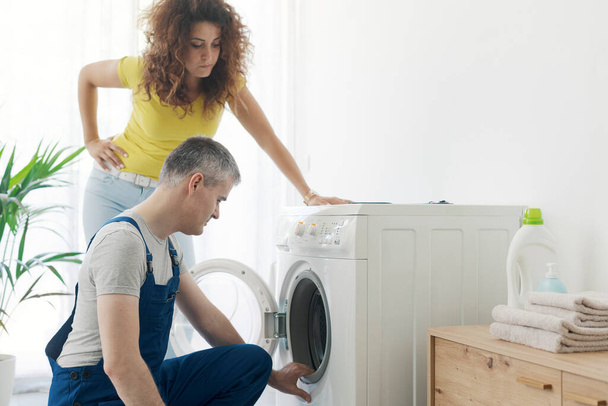 Repairman checking a broken washer, the customer is standing next to him, repair service concept - Photo, image