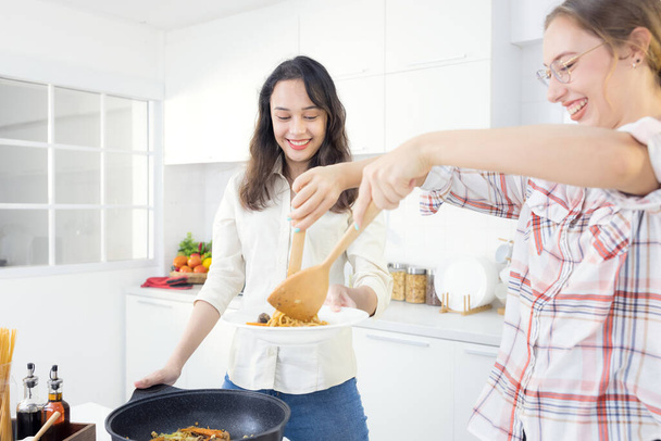 家庭では、 2人の仲間が台所で楽しい時間を過ごしています。一緒に台所でスパゲティを準備する姉妹.台所で二人の女友達 - 写真・画像