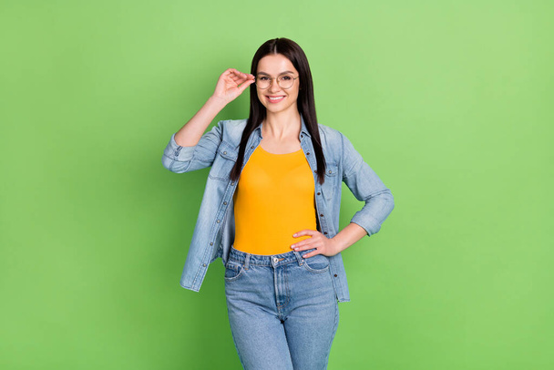 Photo of positive nice brown hairdo lady wear spectacles jeans shirt orange top isolated on green color background - 写真・画像