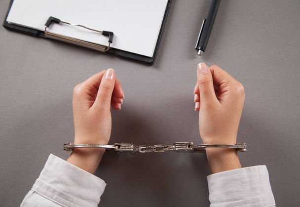 Woman fills out documents with handcuffs. - Фото, зображення