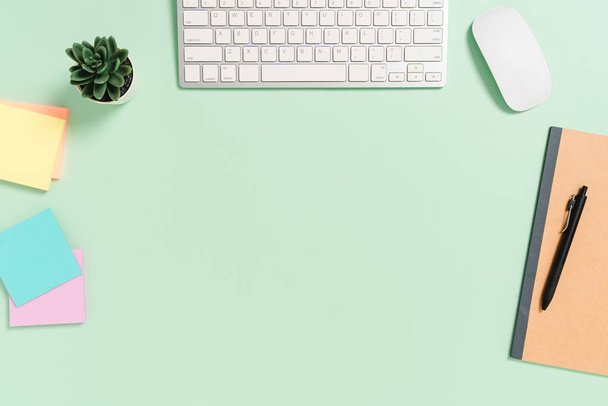 Minimal work space - Creative flat lay photo of workspace desk. Top view office desk with keyboard, mouse and book on pastel green color background. Top view with copy space, flat lay photography. - Photo, Image