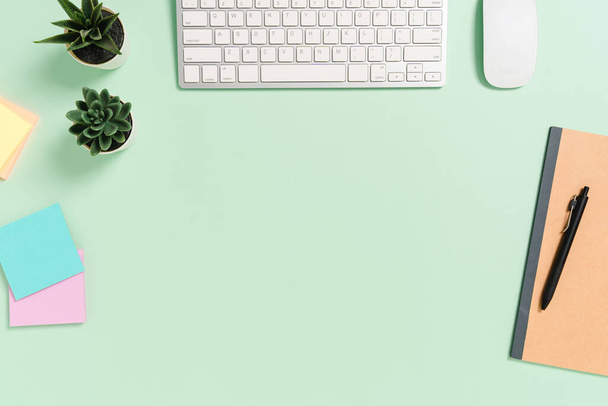 Minimal work space - Creative flat lay photo of workspace desk. Top view office desk with keyboard, mouse and book on pastel green color background. Top view with copy space, flat lay photography. - Photo, Image