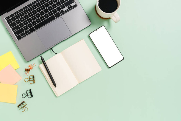 Creative flat lay photo of workspace desk. Top view office desk with laptop, coffee cup and open mockup black notebook on pastel green color background. Top view mock up with copy space photography. - Photo, Image