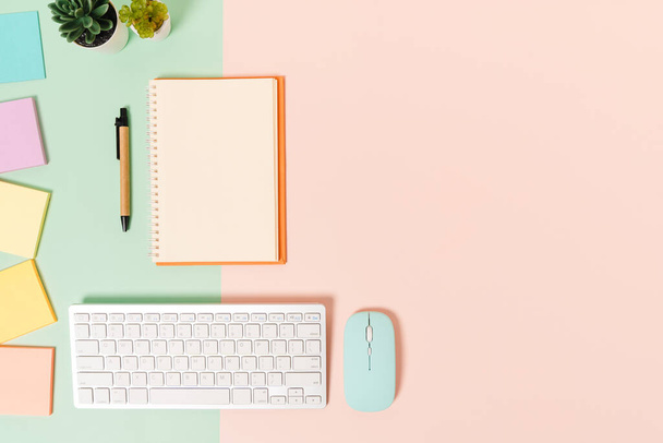 Creative flat lay photo of workspace desk. Top view office desk with keyboard, mouse and open mockup black notebook on pastel green pink color background. Top view mock up with copy space photography. - Photo, Image