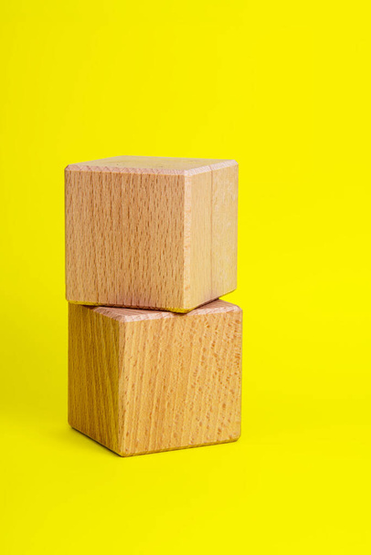 Twee houten kubus vierkant op gele achtergrond copyspace - Foto, afbeelding