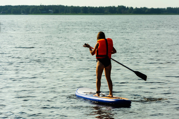 A young mother swims on a standing paddle board . SUP board. Water sports. - Фото, зображення
